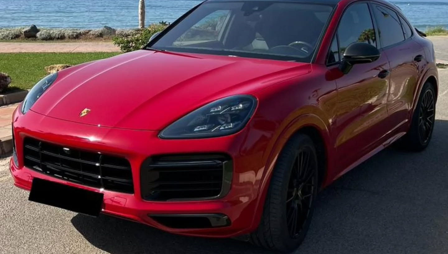 Front-left three-quarter view of red Porsche Cayenne GTS with large front air intakes, LED headlights and sporty SUV stance, Marbella performance SUV rental