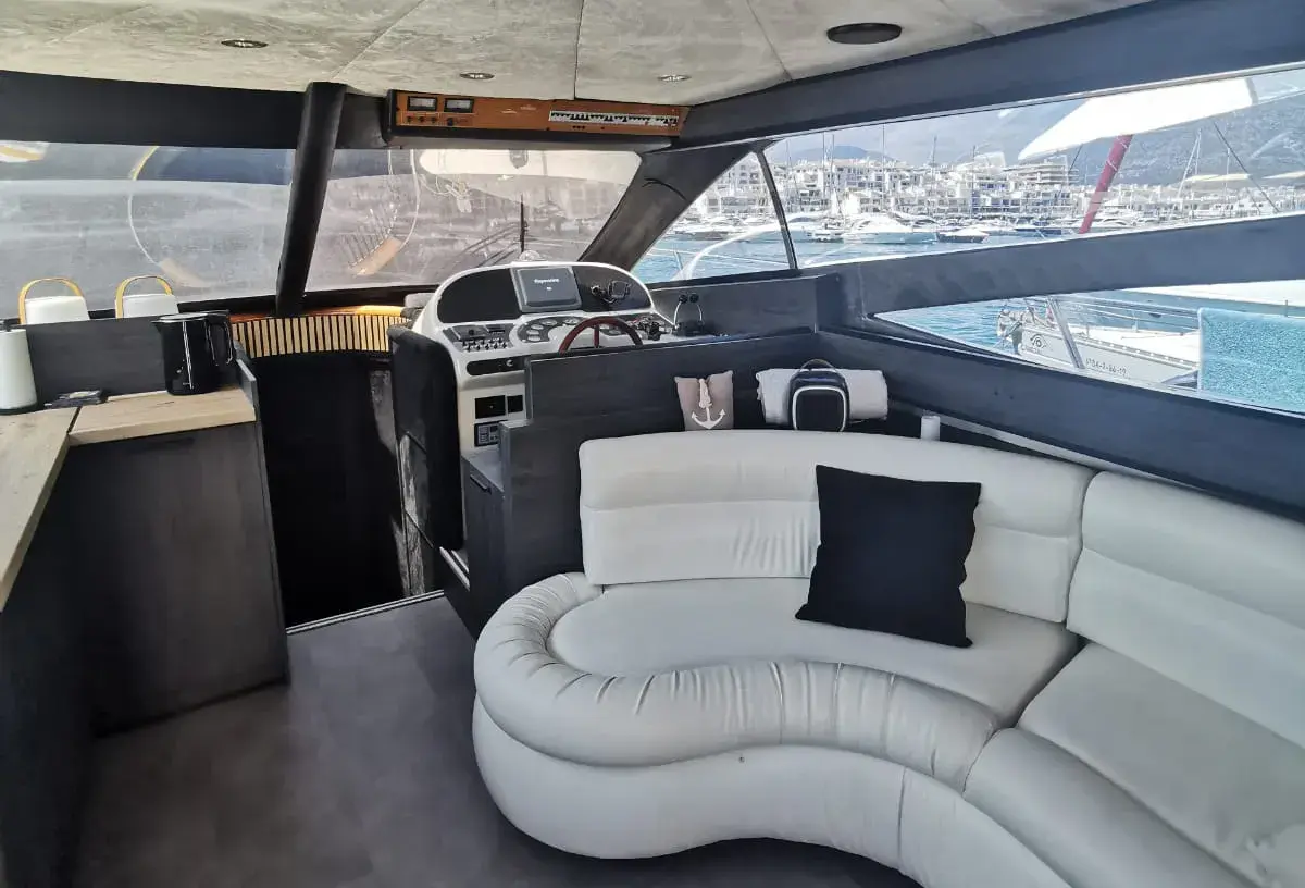 Interior seating area of a Marbella charter yacht with comfortable sofas and large windows looking out over the sea.