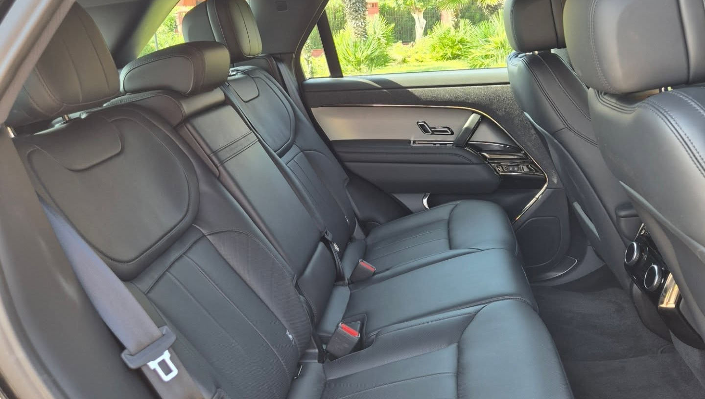 Rear seats of Land Rover Range Rover Sport Hybrid 3.0L with generous legroom and leather upholstery, ideal for three passengers.