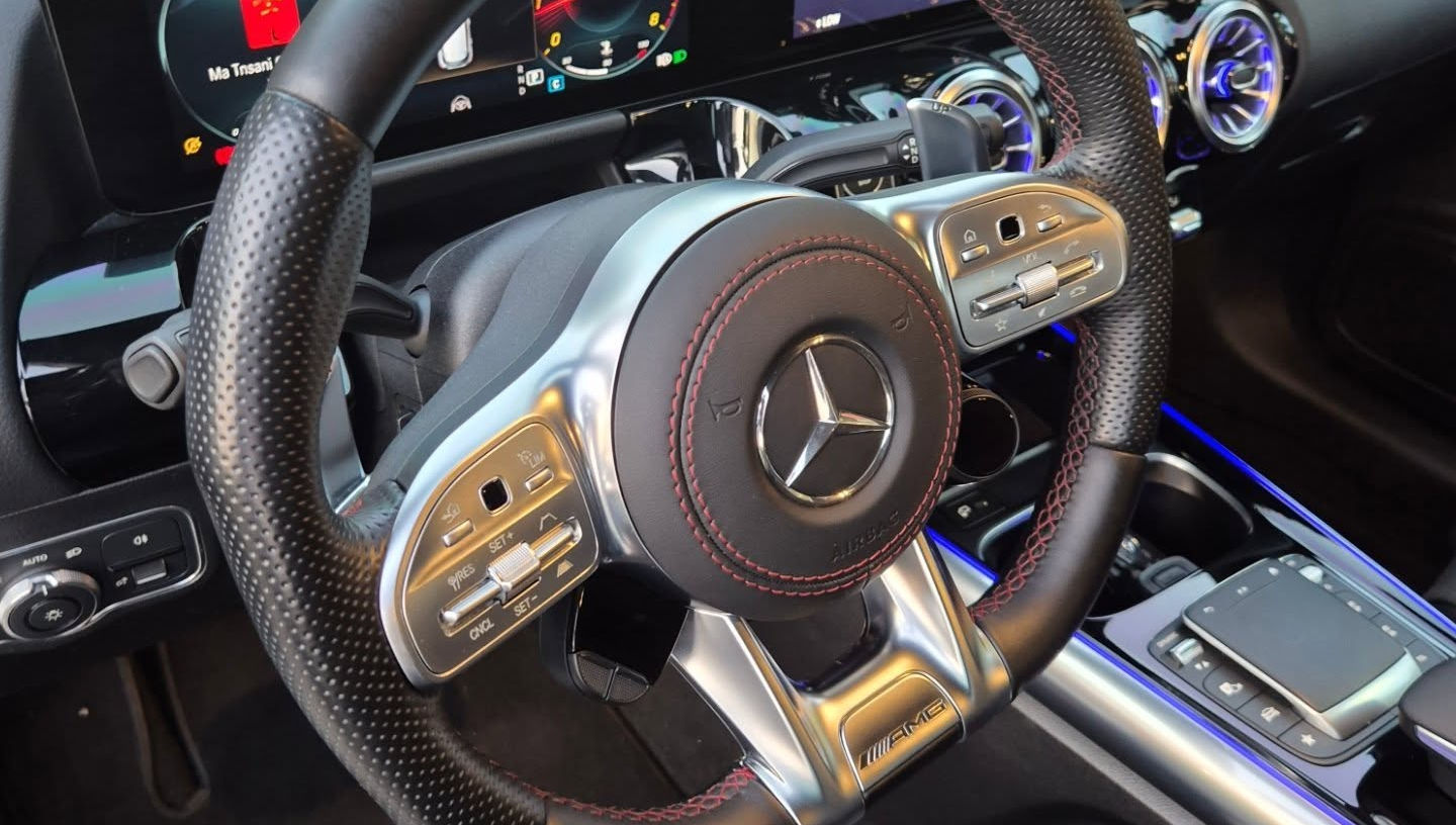 Close-up of Mercedes GLA 200 Brabus steering wheel with multifunction controls and sporty hatchback cockpit.
