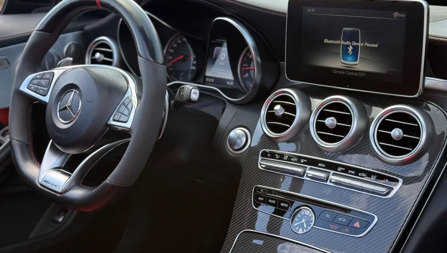 AMG cockpit of Mercedes C63 S Cabriolet with flat-bottom performance steering wheel, digital instrument cluster and central infotainment display, luxury interior Marbella