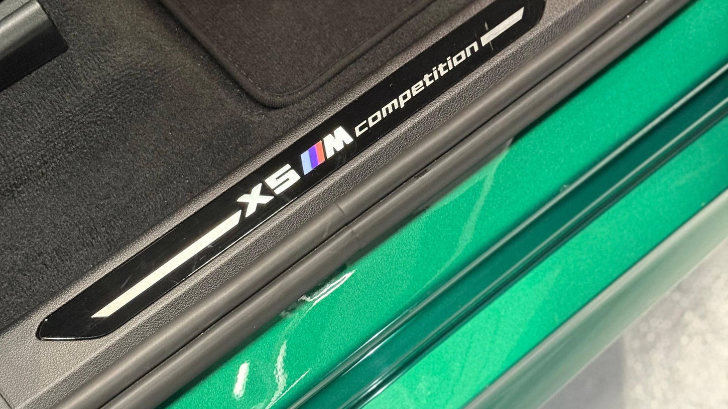 BMW X5M side skirt logo detail with open door on performance SUV rental