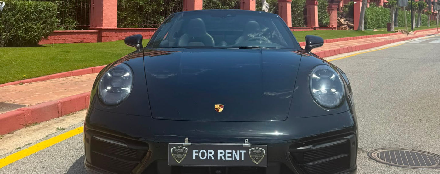 Front view of a black Porsche 911 Targa 4 GTS parked on a luxury Marbella boulevard.