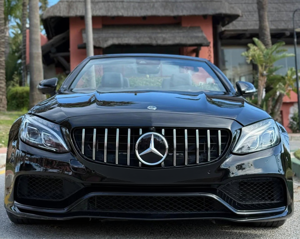 Head-on front view of black Mercedes-AMG C63 S Cabriolet featuring AMG-specific grille, sculpted bonnet and wide performance bumper design, AMG rental Marbella