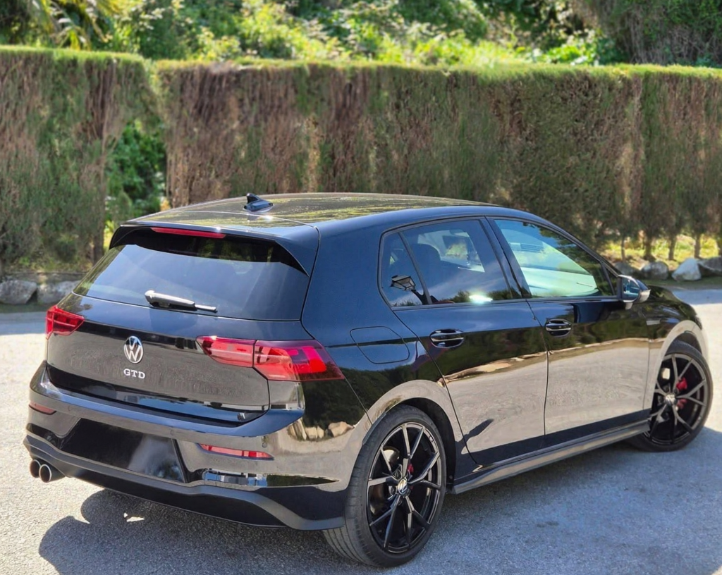 Rear-right three-quarter hero shot of black VW Golf GTD featuring LED tail lights, roof spoiler and twin exhaust outlets, sporty hatchback hire Marbella