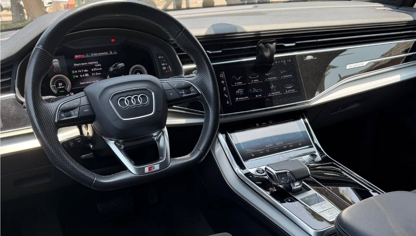 Left side view of Audi Q7 50 TFSI plug-in hybrid dashboard with steering wheel, digital cockpit and driver display.