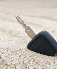 new car key sticking out of sand