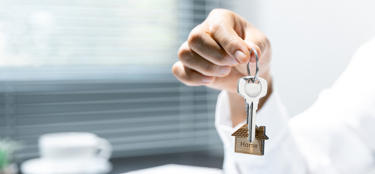 Hand holding house key with home shaped keychain for real estate concept.jpg