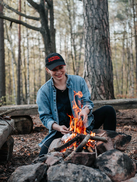 Woman lighting a campfire in the forest