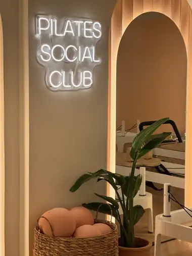 Neon sign beside a mirrored arch and a basket of pilates balls