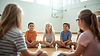 clean friendly website hero image of kids sitting in a circle in a sports hall, calm liste