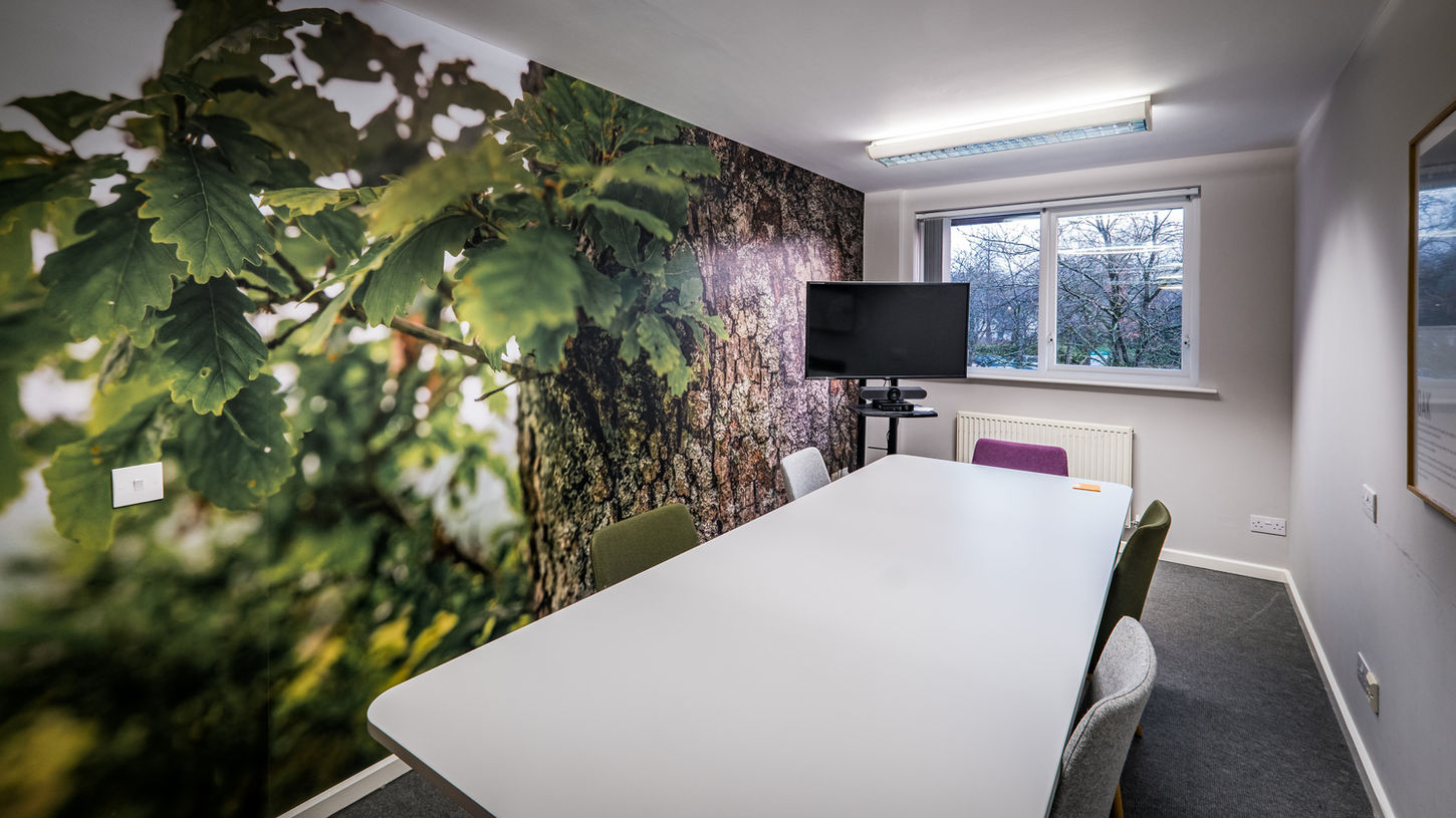 Lake District National Park Authority head office meeting room set in boardroom style with large print covering full wall and AV equipment in corner of room