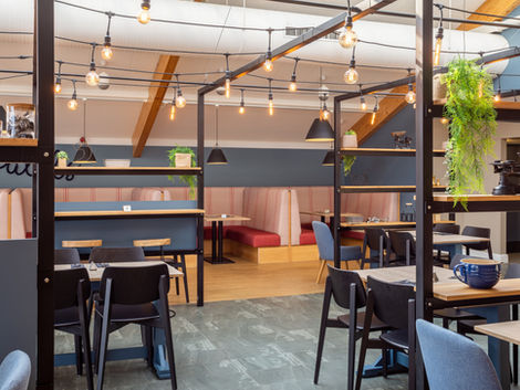 Cafe Oswalds seating including tables and booths with lighting hanging from frame