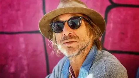 Eye-level view of Todd Snider performing live on stage with acoustic guitar