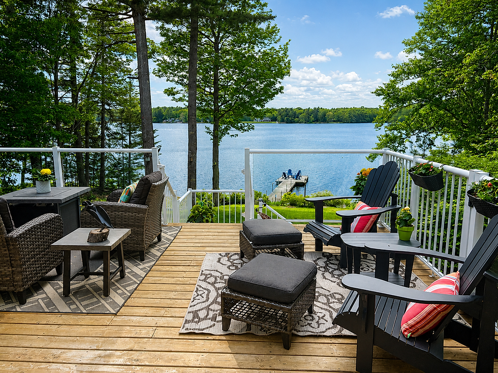 Photo of Betty Jean's deck looking outward to the lake. It is a sunny day and summer furniture is ready.
