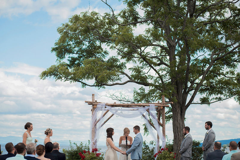 A bride and groom hold hands as they say their vows at their wedding ceremony, overlooking Lake Champlain at Valcour Inn and Boathouse in Peru, NY - Adirondack Wedding Photographer