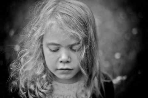 An Adirondack black and white family portrait of a little girl in a jean jacket with her messy blonde hair and her eyes closed