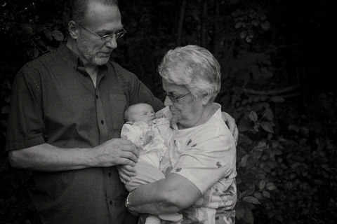 Grandparents hold their newborn granddaughter for a family photo in Lake Placid, NY