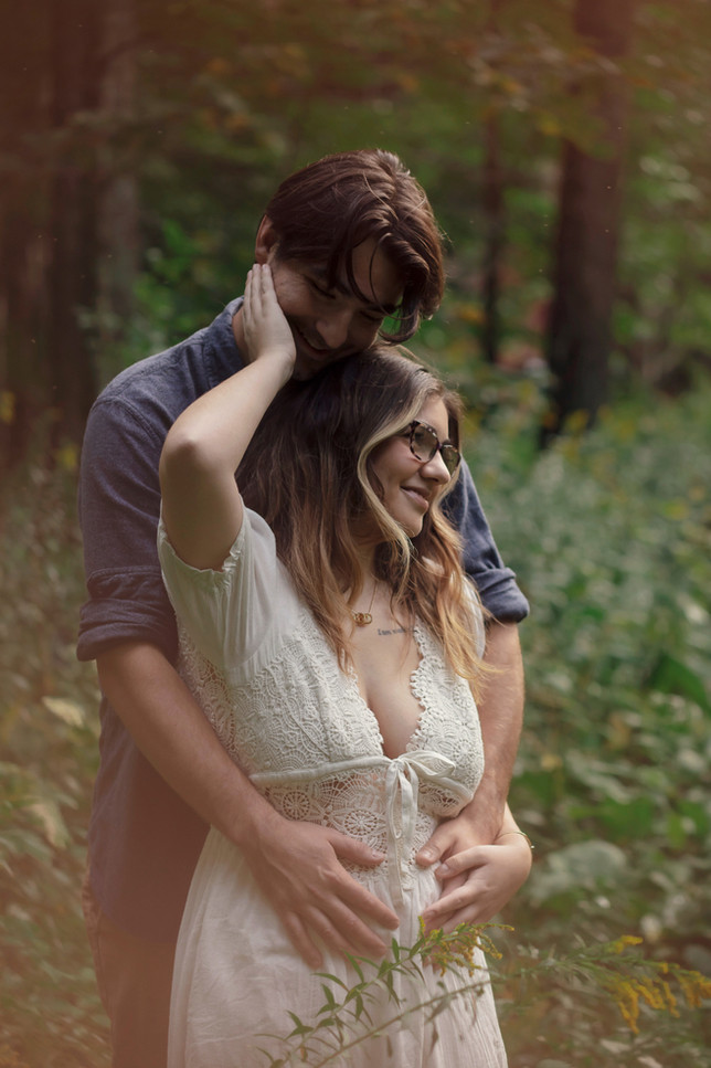 Engaged couple in a forest with golden light in Plattsburgh NY during early Summer