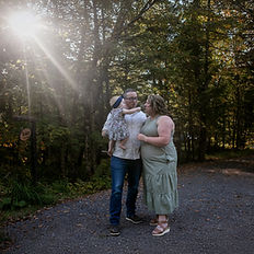 A family of three plays in a sun flare for family photos in the Adirondacks