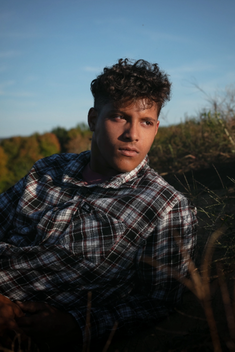 A boy looks in the distance during golden hour for his Senior photos