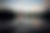 A young woman stands on a stool in the lake at sunset wearing a burgundy dress in a Adirondack lake