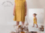 A little girl wearing a yellow dress on the cover of a dress pattern by 'Tiny Design'.