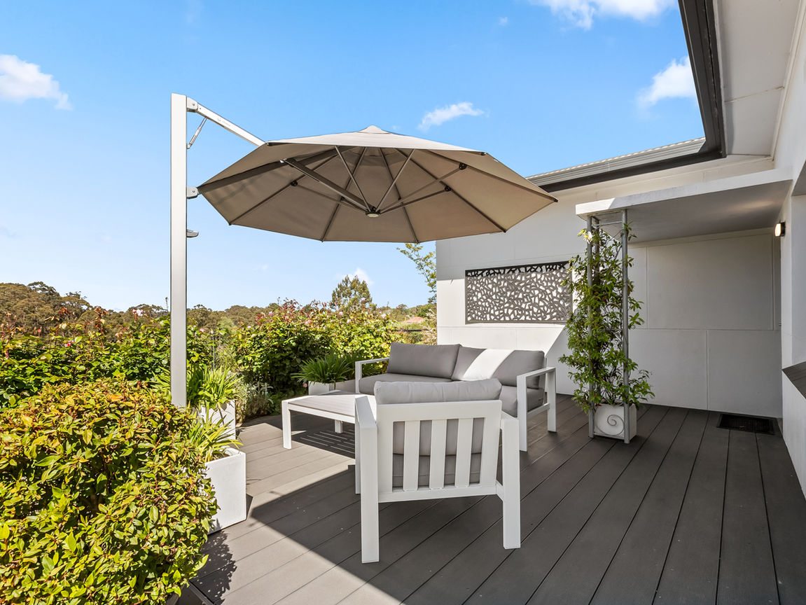 a white outdoor setting on decking with a parasol