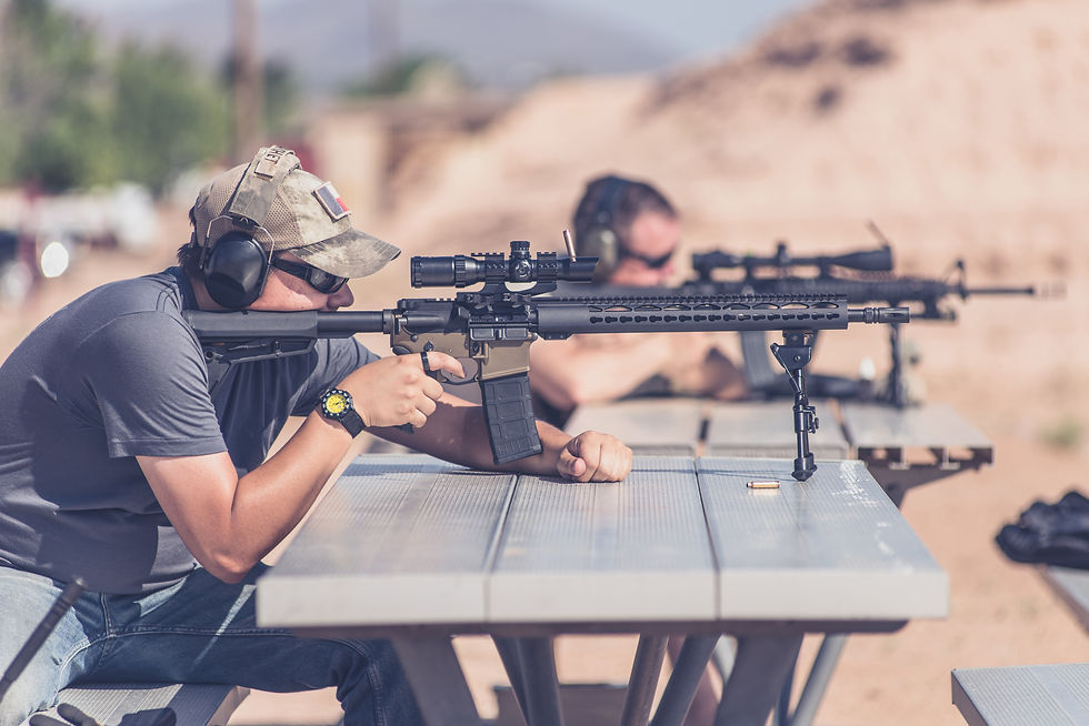 Man firing black rifle on desert range bench rest with bipod.jpg