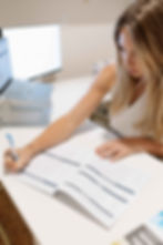 Female sitting at a desk writing on a document