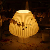 Soft light lamp resting on a table with flowers encroaching on either side
