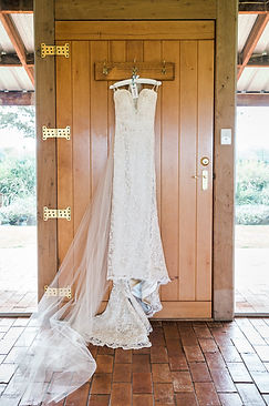 A Jennifer Go couture gown hangs on a door
