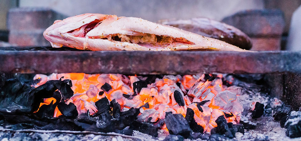 A fish being grilled over coals on a Catch and Cook tour in Belize