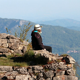 A man sits meditatively on an ancient wall