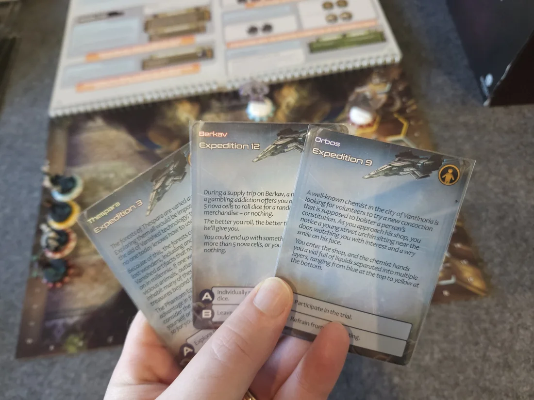 A player holds expedition cards for Berkav, Thespara and Orbos