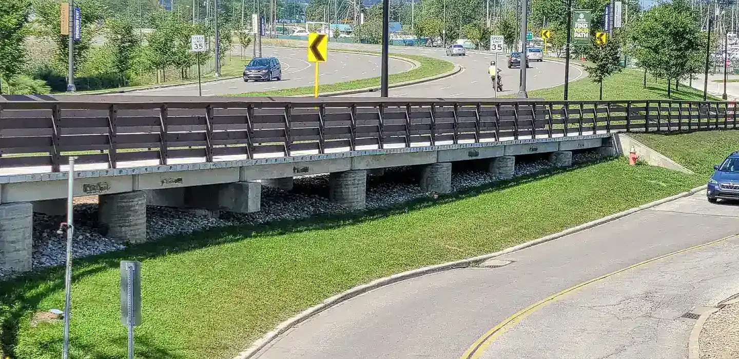 Pedestrian bridge that runs adjacent to a two lane road.