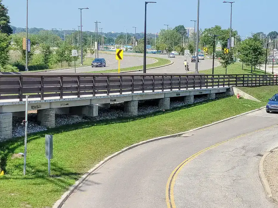 Pedestrian bridge that runs adjacent to a two lane road.