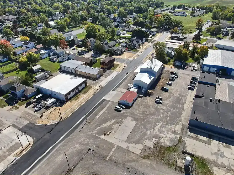 Aerial photo of a newly paved asphalt roadway, new concrete sidewalks, and surrounding buildings looking to the Northeast