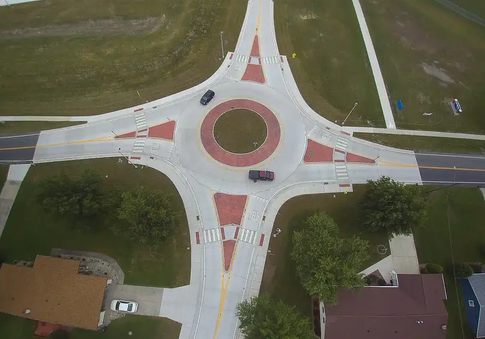 Aerial photo of a concrete 4 leg roundabout with cars passing through.