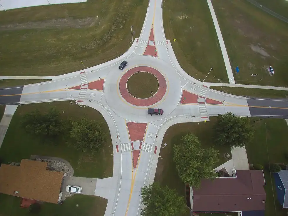 Aerial photo of a concrete 4 leg roundabout with cars passing through.