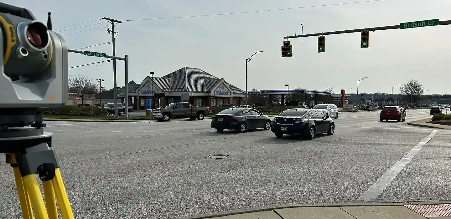 A Trimble scanner in the foreground positioned to collect data for the busy signaled 4 way intersection behind