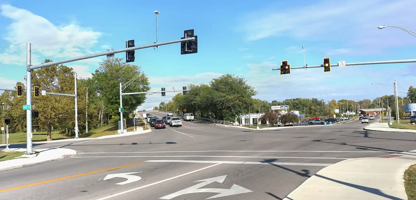 5-way signaled intersection looking towards a bridge queued with cars.