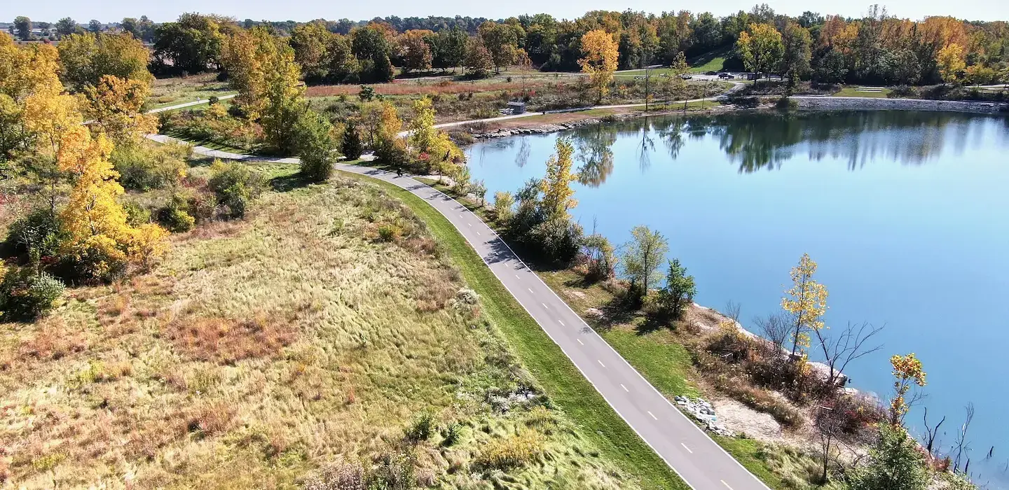 Aerial Photo of an asphalt Multi-Use Trail (MUP) between a grassy field and a pond.