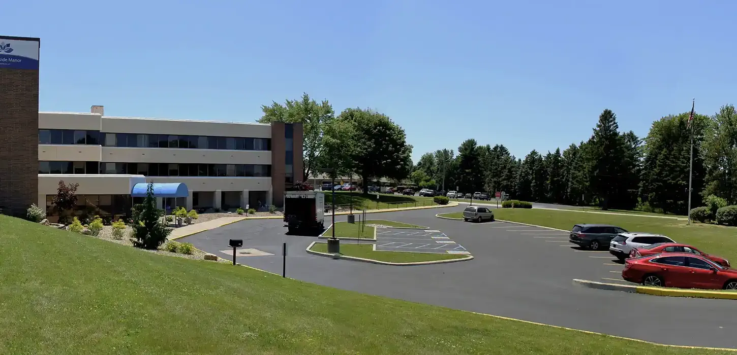 panoramic photo of retirement and healthcare facility entrance and newly improved lighted front asphalt parking lot.