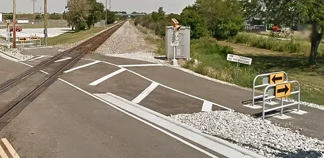 Multi-Use bike Path (MUP) running perpendicular to railroad tracks. There are painted traffic markings.