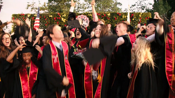 freshly graduated students throwing their hats in the air