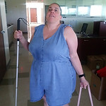 Linda Coccovizzo wearing a blue romper holding a white cane and a pink purse.
