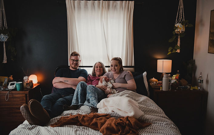 Family in bed with midwife and newborn