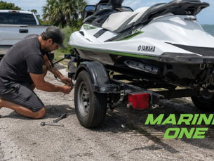 Man working on his jet ski trailer on the side of the road