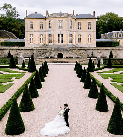 Newlyweds posing with a Chateau in France as a background